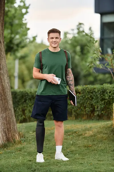 A cheerful young man stands confidently in the park, showcasing his prosthetic leg while smiling warmly. — Stock Photo