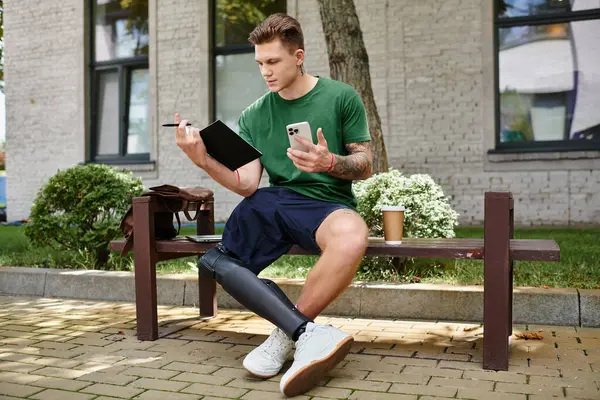 A young and handsome man sits on a bench, sketching while sipping coffee, showcasing his creativity and resilience. — Stock Photo