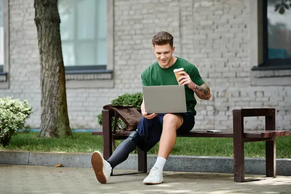 Ein junger Mann mit Beinprothese nippt an seinem Kaffee und konzentriert sich auf seinen Laptop in einem lebhaften Outdoor-Ambiente. — Stockfoto