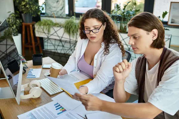 A plus size woman and her male friend share ideas while working in a vibrant office. — Stock Photo