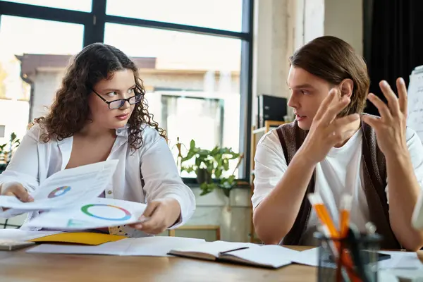 Two friends engage in an animated discussion while reviewing documents at a shared desk. — Stock Photo