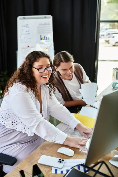 A young plus size woman and her male friend are happily engaged in teamwork at a desk. — Stock Photo