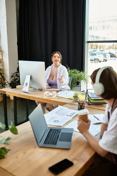 Una mujer de talla grande y su amigo masculino participan en una discusión animada mientras trabajan. - foto de stock