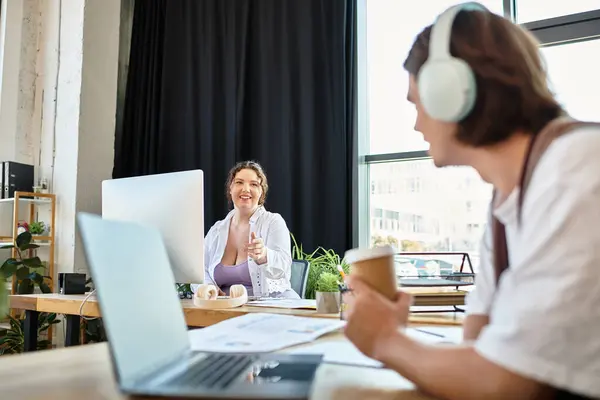 A cheerful young plus size woman shares a delightful moment with her male companion at work. — Stock Photo