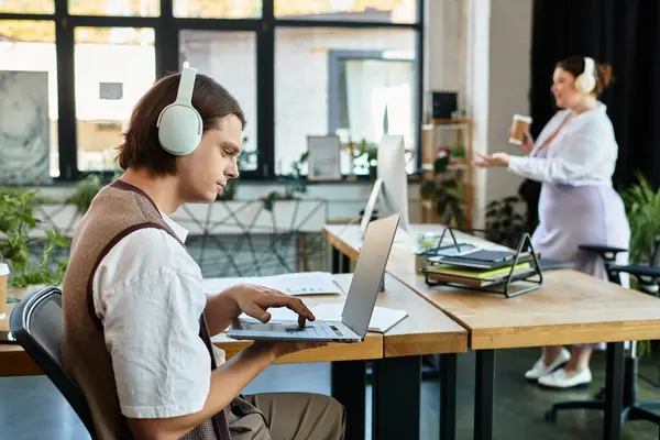 A young plus size woman chats animatedly with her friend, who focuses on his laptop. — Stock Photo