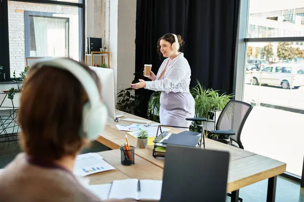 Eine junge Plus-Size-Frau teilt bei der Arbeit begeistert Ideen mit ihrem männlichen Freund. — Stockfoto