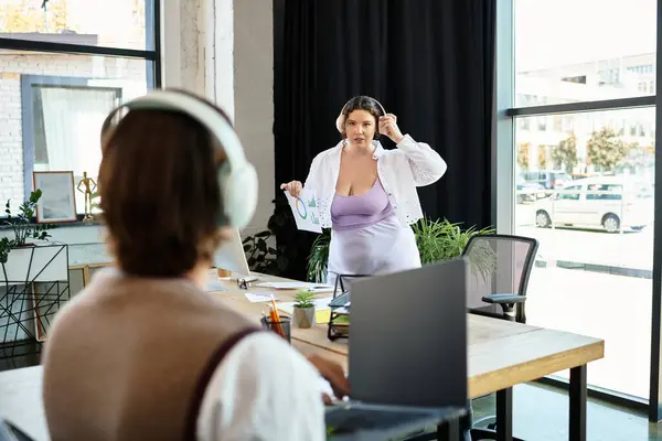 Una donna plus size condivide le idee con entusiasmo con la sua amica in un ambiente vibrante ufficio. — Foto stock