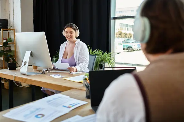 A young plus size woman shares ideas with her male friend in a bright and inviting workspace. — Stock Photo