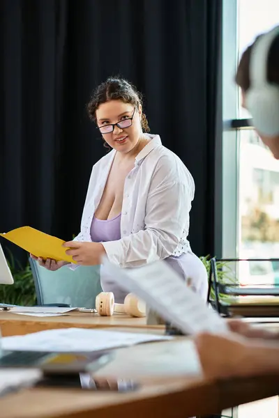 The young woman engages with her friend while holding a folder of notes and ideas. — Stock Photo