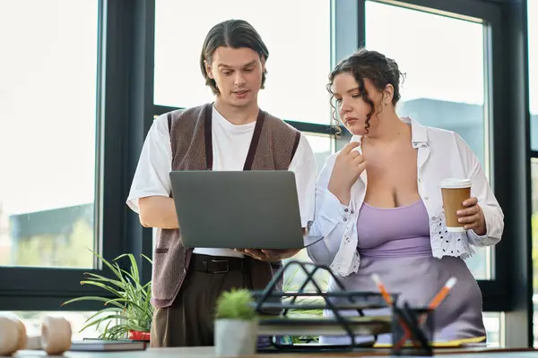 A young plus size woman and her male friend review work on a laptop while enjoying coffee. — Stock Photo
