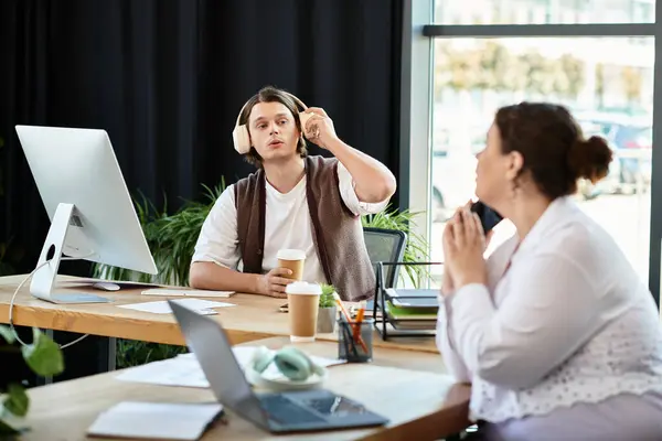 A young plus size woman listens intently while her male friend shares ideas in a bright office. — Stock Photo