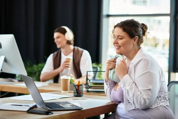 Una alegre mujer de talla grande trabaja con su amigo varón en una oficina creativa. - foto de stock