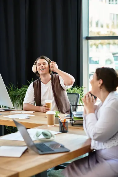 A cheerful young woman enjoys a light moment with her male friend in a modern workspace. — Stock Photo