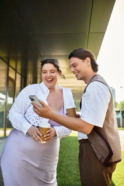 A young woman and her male friend laugh together while enjoying their coffee outdoors. — Stock Photo