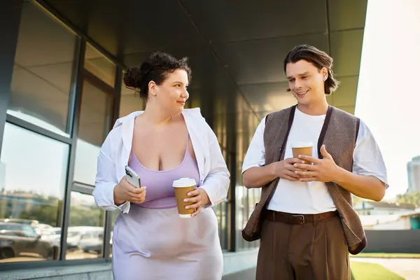 Deux amis profitent d'une conversation animée tout en sirotant un café à l'extérieur d'un bâtiment moderne. — Photo de stock