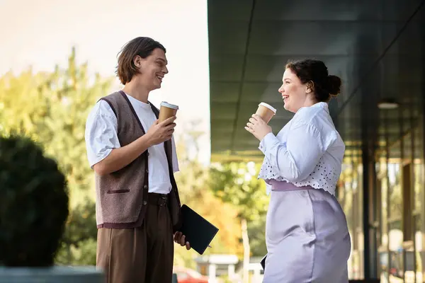 Une jeune femme de taille plus profite d'une conversation joyeuse avec son ami masculin, les deux tenant un café. — Photo de stock