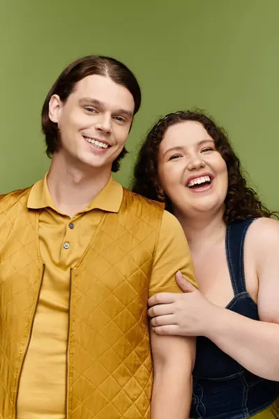 A young plus size woman and her male friend share a hearty laugh in a colorful studio backdrop. — Stock Photo