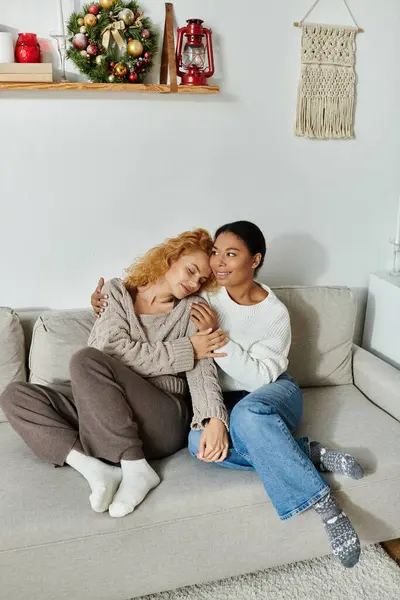 Two women share a tender moment on the couch, surrounded by warmth and comfort in their home. — Stock Photo