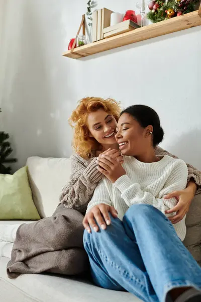 Two women embrace lovingly on a sofa, radiating warmth and happiness in their cozy home. — Stock Photo