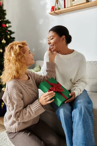 Una pareja comparte un momento dulce en casa, abriendo con entusiasmo un regalo juntos. - foto de stock