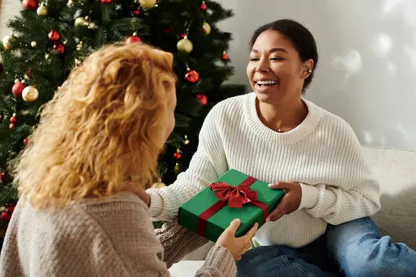 A joyful couple exchanges gifts while enjoying their cozy holiday atmosphere. — Stock Photo