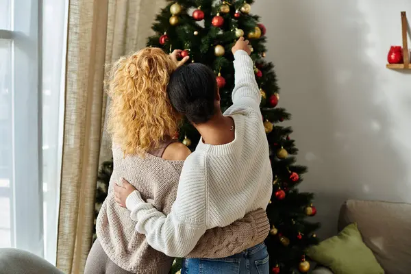 Una feliz pareja comparte un momento cálido mientras pone adornos en su árbol de Navidad en casa. — Stock Photo