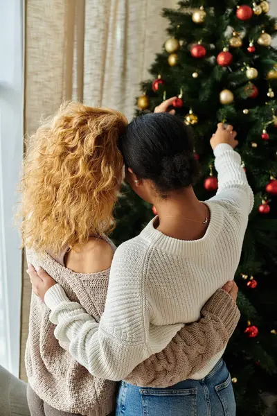 A loving couple embraces while adorning their Christmas tree with ornaments and joy. — Stock Photo