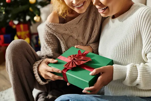 Двоє закоханих партнерів поділяють сердечний момент, обмінюючись красиво загорнутим подарунком разом. — стокове фото