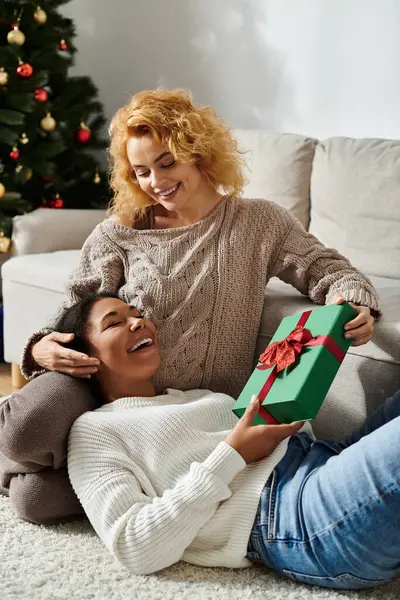 A happy couple exchanges gifts on a cozy holiday at home, filled with love and cheer. — Stock Photo