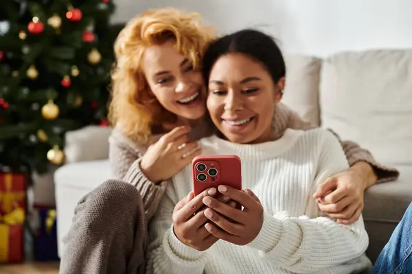 A couple enjoys quality time together, laughing and sharing smiles while looking at a smartphone. — Stock Photo