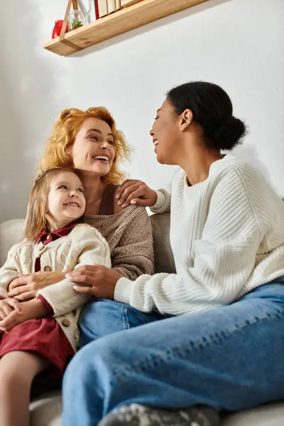 Ein freudiger Familienmoment, den ein lesbisches Paar und ihre Tochter in einer warmen häuslichen Umgebung teilen. — Stockfoto