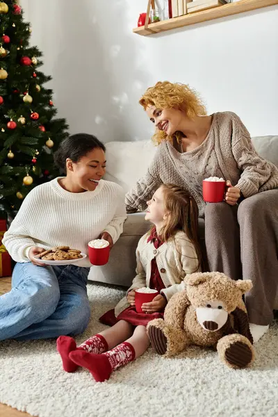 A loving couple and their daughter share laughter and treats in a festive, cozy living room. — Stock Photo