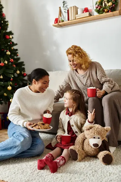 The cheerful couple shares cookies and cocoa with their daughter by the festive tree — Stock Photo