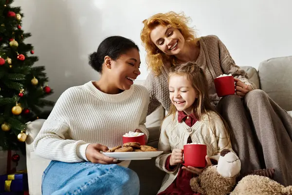 A joyful family gathers on the couch, sharing laughter and delicious treats in their festive home. — Stock Photo