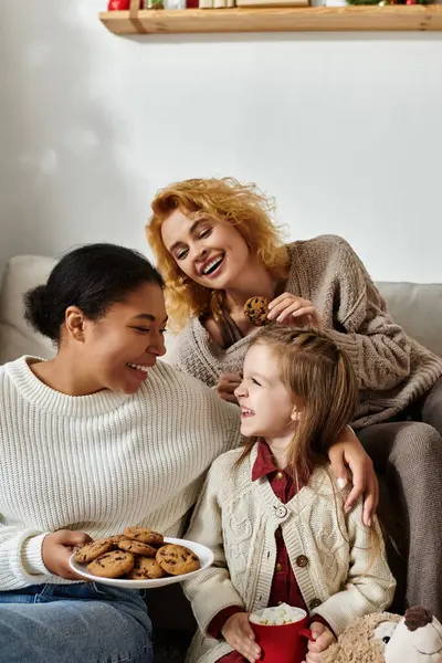 A joyful afternoon with a lesbian couple and their daughter sharing cookies and laughter. — Stock Photo