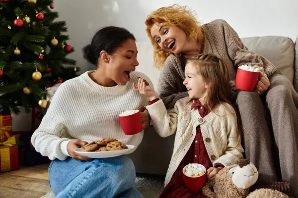 A warm moment of a lesbian family sharing cookies and drinks together in their cozy living room. — Stock Photo