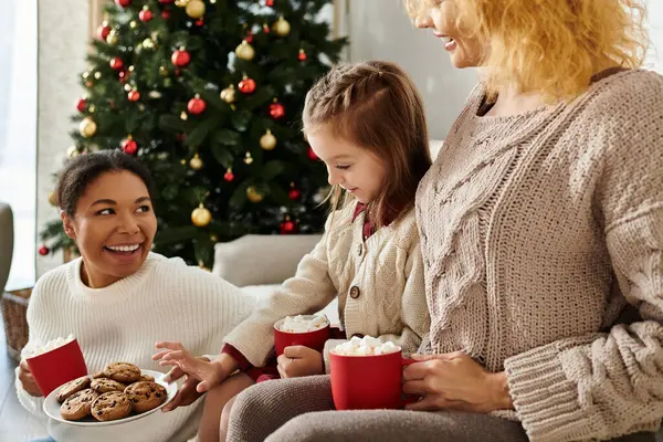 A loving couple shares laughter with their daughter while savoring hot cocoa and cookies. — Stock Photo