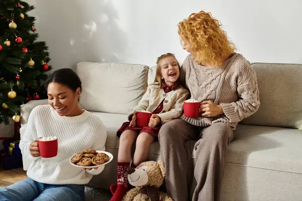 A loving couple shares laughter with their daughter while enjoying warm drinks at home. — Stock Photo