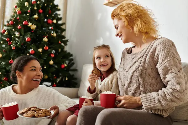 Ein fröhliches Paar und ihre Tochter teilen Kekse und heißen Kakao und genießen die Feiertagsstimmung. — Stockfoto