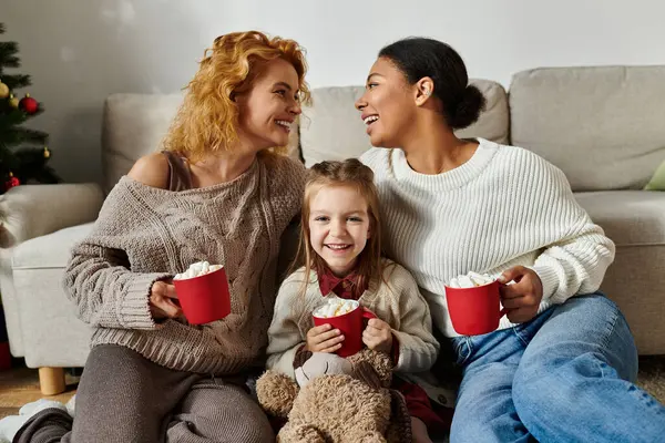 A loving couple enjoys sipping cocoa with their smiling daughter at home in a cozy atmosphere. — Stock Photo
