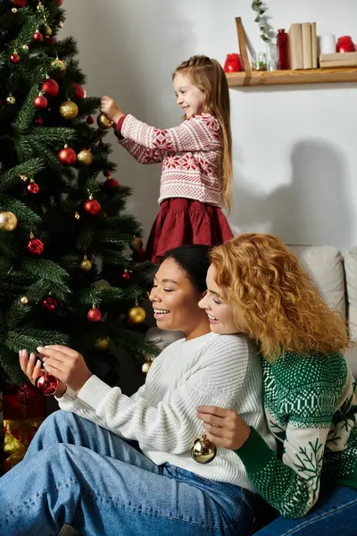 This cheerful family spends quality time decorating their Christmas tree, creating joyful memories. — Stock Photo