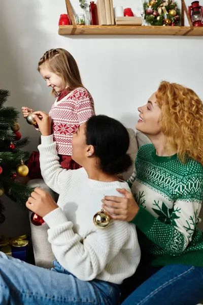 A warm family atmosphere filled with laughter as they decorate a Christmas tree together. — Stock Photo