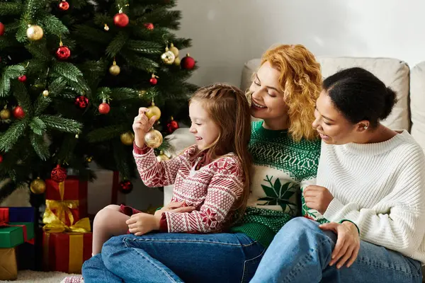 Um casal amoroso compartilha um momento quente com sua filha enquanto decoram para o Natal. — Fotografia de Stock