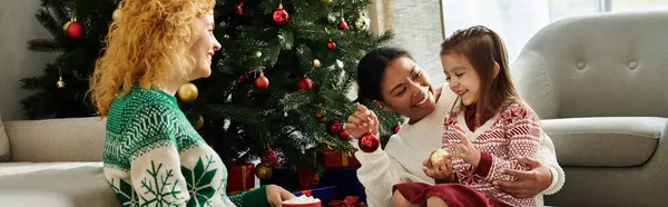 A joyful couple enjoys festive moments with their smiling daughter by the Christmas tree. — Stock Photo