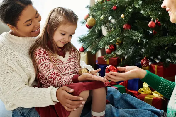 A loving couple shares a warm moment with their daughter while decorating the Christmas tree. — Stock Photo