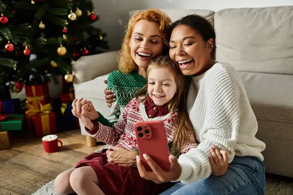A joyful family celebrates together as a couple takes a selfie with their daughter at home. — Stock Photo