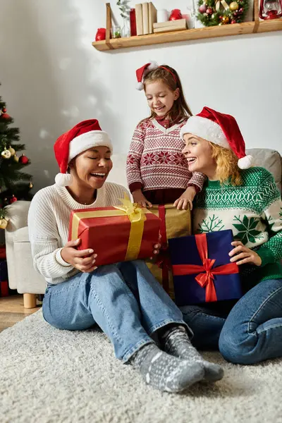 A happy couple and their daughter share laughter while opening presents during the festive season. — Stock Photo