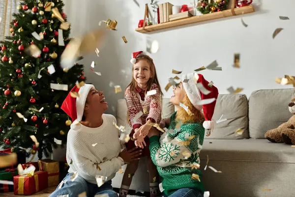 A loving couple and their daughter celebrate Christmas while confetti falls around them. — Stock Photo
