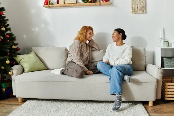Two women share joyful moments on the couch in their warm, inviting living room. — Stock Photo