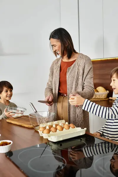 Eine fröhliche Großmutter teilt Momente mit ihren Enkeln und zaubert gemeinsam in der Küche festliche Leckereien. — Stockfoto